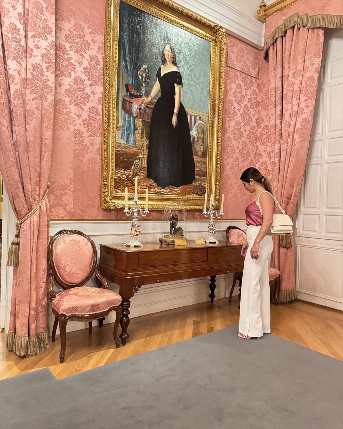 Onesy Carranza observa una sala de museo bajo un retrato clásico de una mujer vestida de negro
